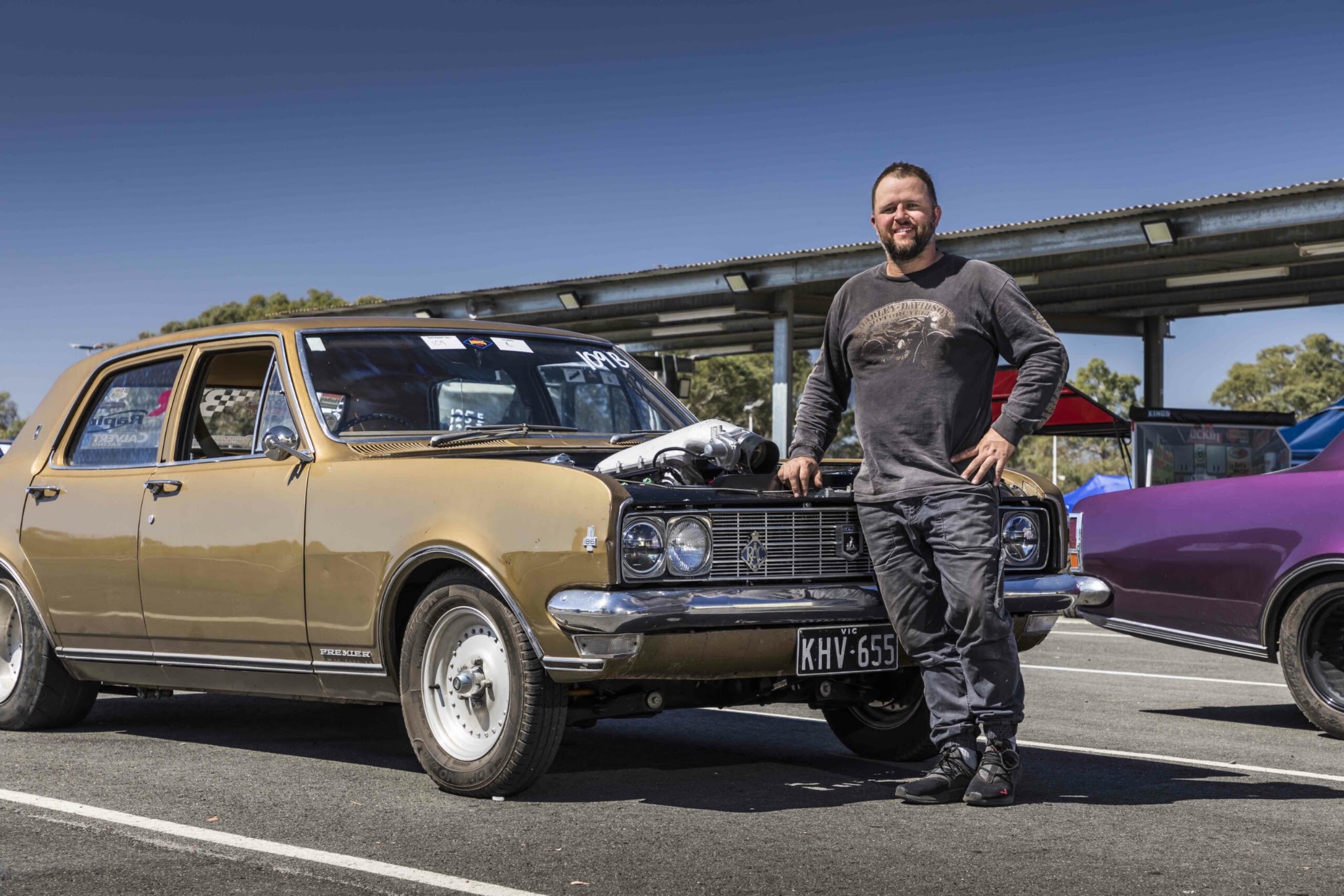 Corey Edwards beside his gold 1969 Holden HT Premier with the bonnet raised